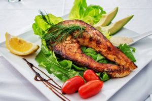 photo of cooked salmon on a plate with salad