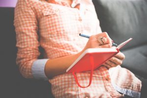 Lady writing in an orange journal